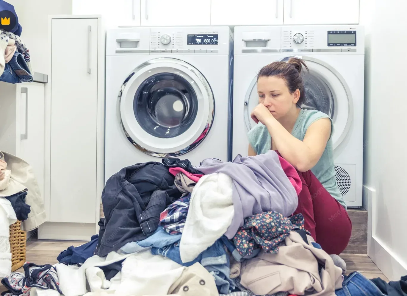 Overwhelmed resident sitting next to a small in-unit washer with a large pile of laundry