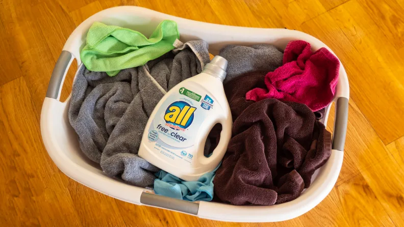 Basket of dirty laundry with a bottle of all free and clear on top